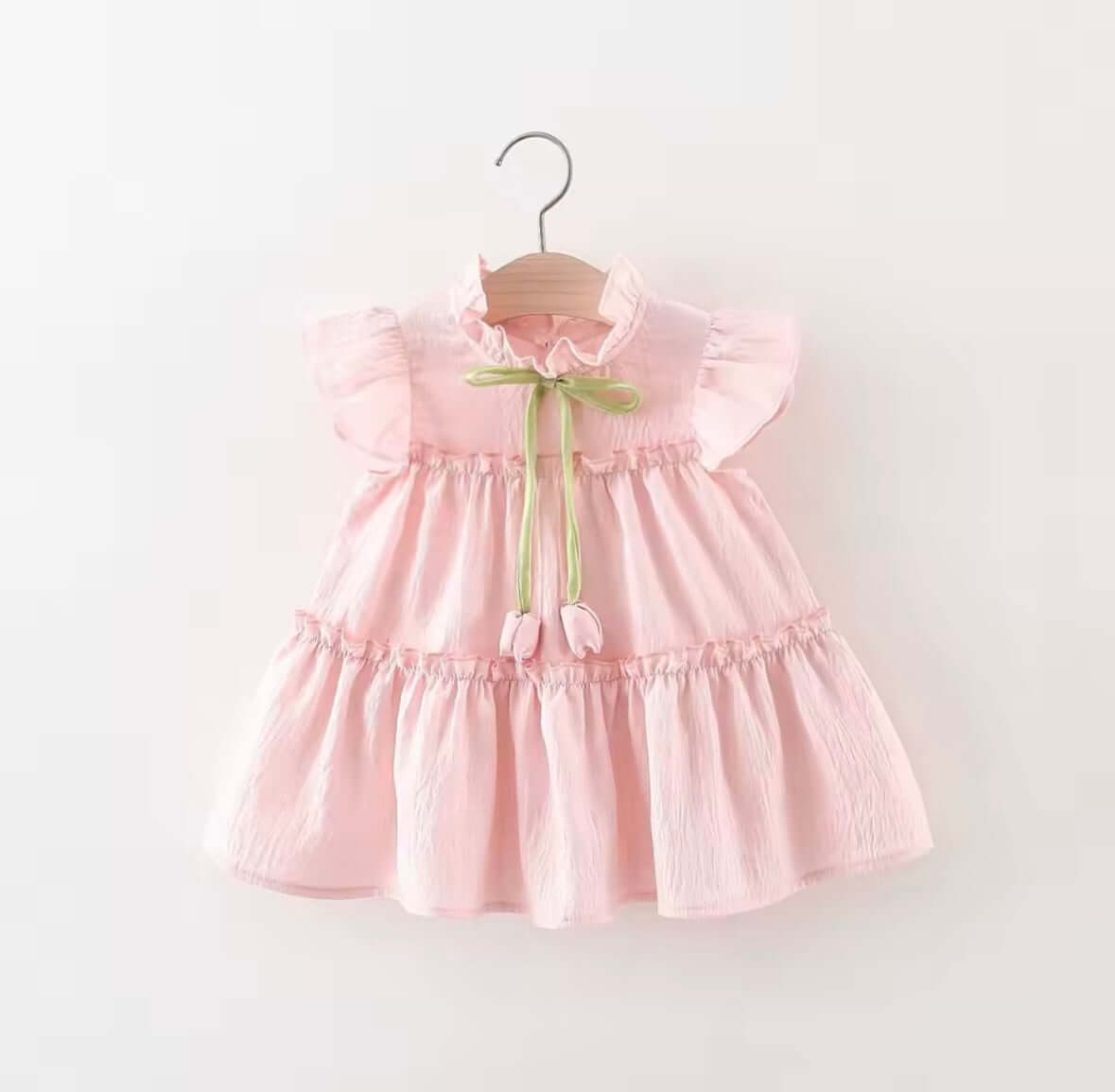 Blush pink ruffle dress with flutter sleeves and green bow tie, perfect for magical moments and playful occasions.