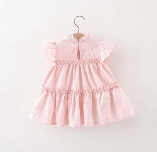 Blush pink ruffle dress with flutter sleeves and tiered layers, perfect for magical moments and playful adventures.