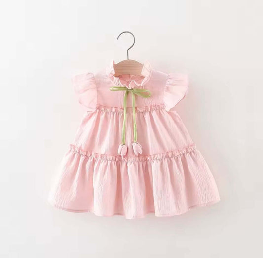 Blush pink ruffle dress with flutter sleeves and green bow tie, perfect for magical moments and playful occasions.