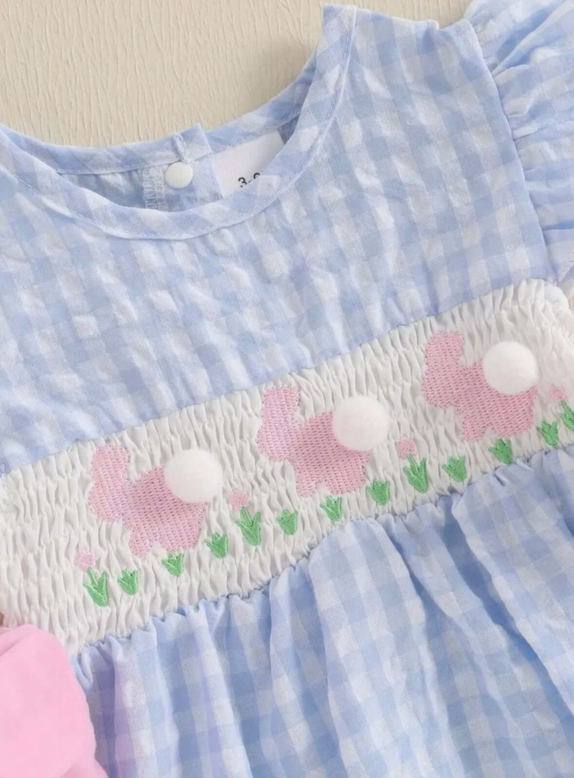 Blue gingham baby dress featuring cute rabbit embroidery and ruffled sleeves, perfect for spring and summer occasions.